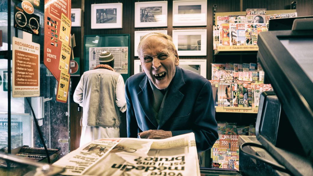 Vieil homme hilare devant le journal